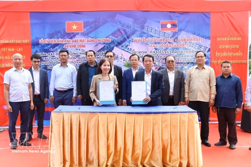 Participants sign a handover and acceptance record for the construction site and break ground for a project to build the Khammuon provincial Boarding School for Ethnic Minority Students. (Photo: VNA)