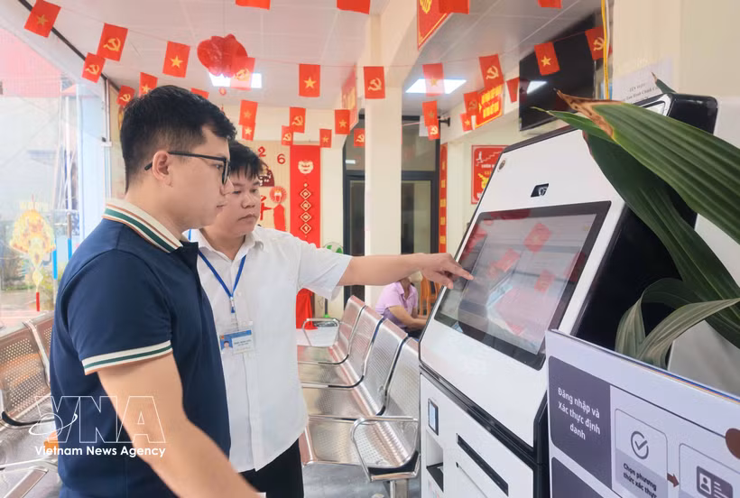 A civil servant at the Chi Lang commune Public Service Centre in Lang Son province guides a resident in how to use an AI-supported public service kiosk. (Photo: VNA)