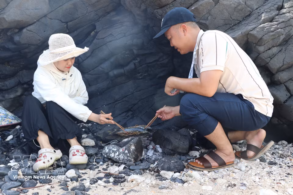 Visitors experience grilling freshly caught fish at Hon Nhan. (Photo: Dinh Huong/VNA)