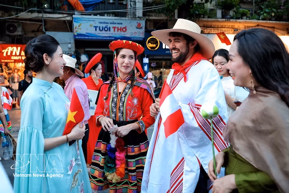 Members of the Peruvian delegation in traditional costumes interact with Hanoi women ahead of the parade at the “Colours of the World” street festival. (Photo: VNA)
