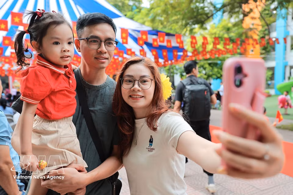 Parents take souvenir photos of their children before they enter the classroom at Kim Lien Kindergarten (Hanoi). (Photo: VNA)