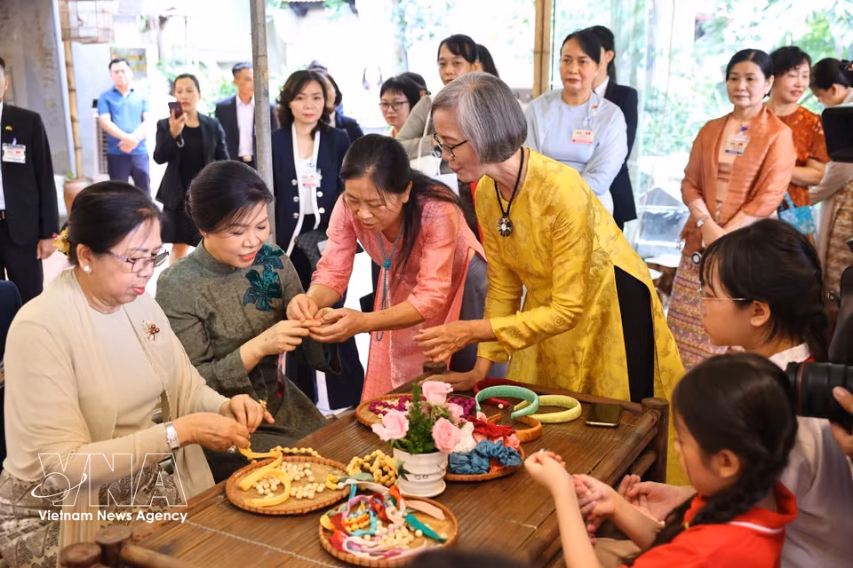 Ngo Phuong Ly (spouse of General Secretary of the Communist Party of Vietnam Central Committee and President To Lam), and Kyu Kyu Hla (spouse of Myanmar President Min Aung Hlaing) join local children in making silk-bead bracelets at Van Phuc Silk Village. (Photo: VNA)