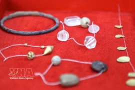 Glass beads, gold-coloured metal beads and leaf-shaped objects uncovered in the tombs. (Photo: VNA)