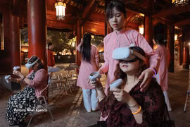 Tourists experience writing calligraphy through virtual reality at Hanoi's Temple of Literature. (Photo: VNA