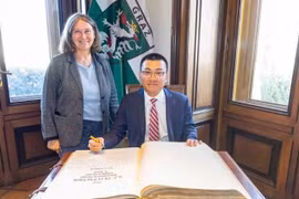 Elke Kahr, former Deputy Chairwoman of the Communist Party of Austria Central Committee and Mayor of Graz, and Vietnamese Ambassador to Austria Vu Le Thai Hoang (sitting) sign the city of Graz’s guest book. (Photo courtesy by the Vietnamese Embassy in Austria)