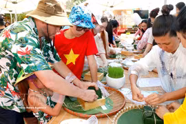 Foreign tourists experience wrapping up Chung cake on the occasion of Vietnam's Lunar New Year. (Photo: VNA)