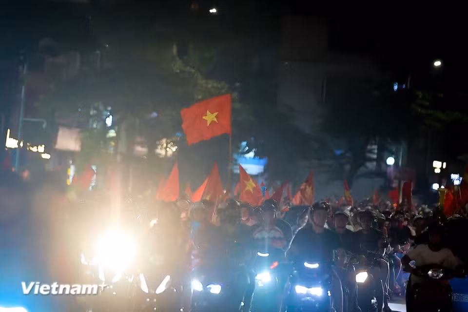 As the night wears on, the celebrations reach a fever pitch, with giant national flags flying in the dazzling lights. (Photo: VietnamPlus)