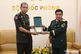 Major General Nguyen Ba Luc (R) presents a gift to Lieutenant General Nim Balene. (Photo: Qdnd.vn)