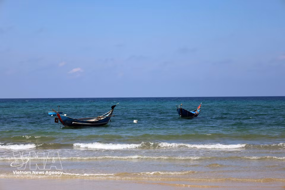 Small fishing boats anchored in crystal-clear blue waters. (Photo: Do Truong/VNA)