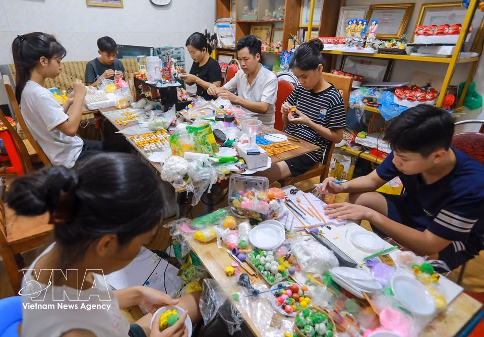 Artisan Dang Van Hau instructs young people as they create their own to he artworks. (Khanh Hoa/VNA)