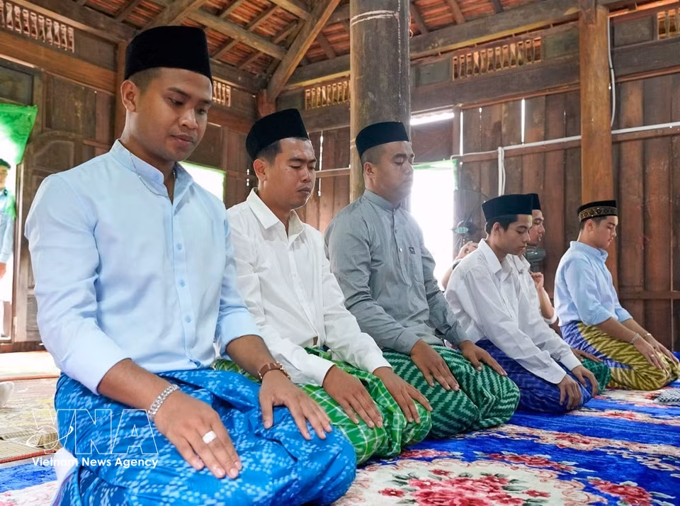 Cham Muslim men in traditional attire make their way together to the mosque for prayers. (Photo: Khanh Hoa/VNA)