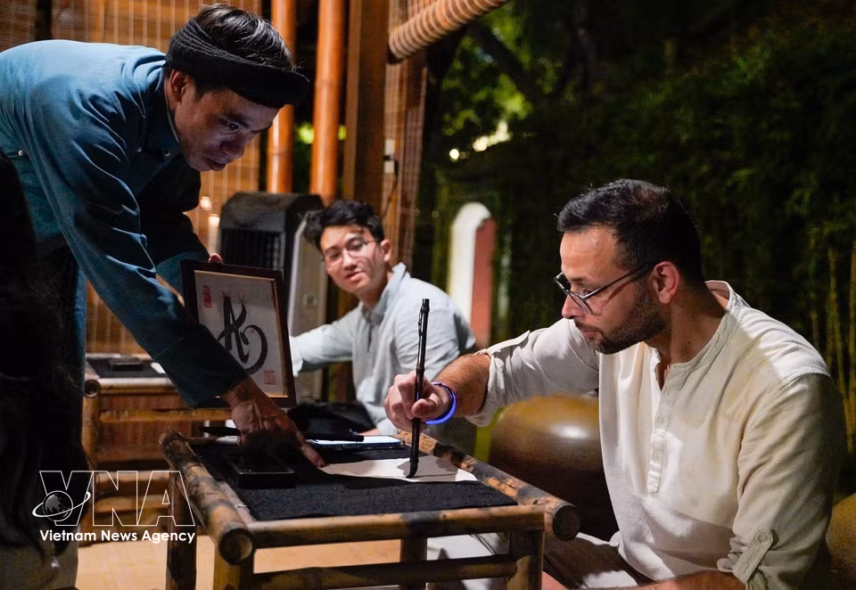 Visitors take part in a calligraphy-writing experience. (Photo: Khanh Hoa/VNA)