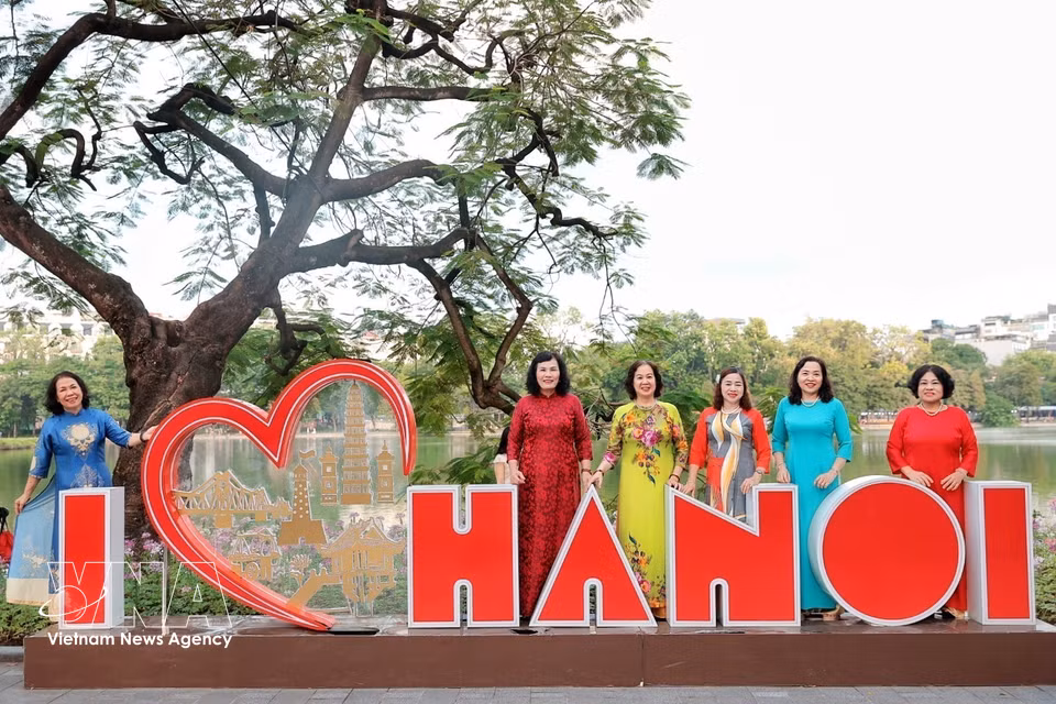 Older women in ao dai (traditional long dress) enjoy a morning in autumn. (Photo: Pham Tuan Anh/VNA)