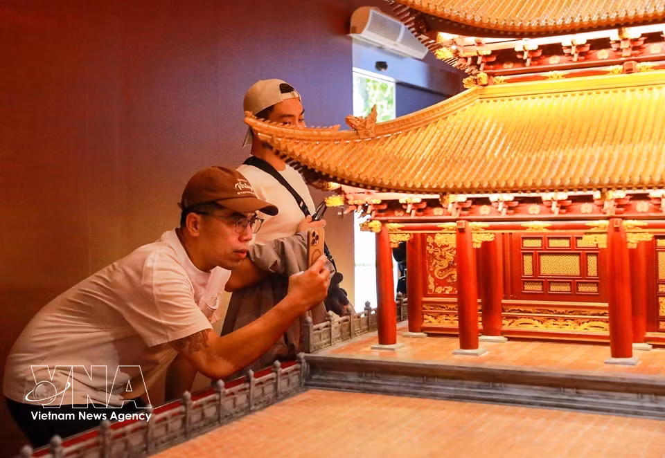Visitors look at a reconstruction model of Kinh Thien Palace displayed at the exhibition. (Photo: Khanh Hoa/VNA)