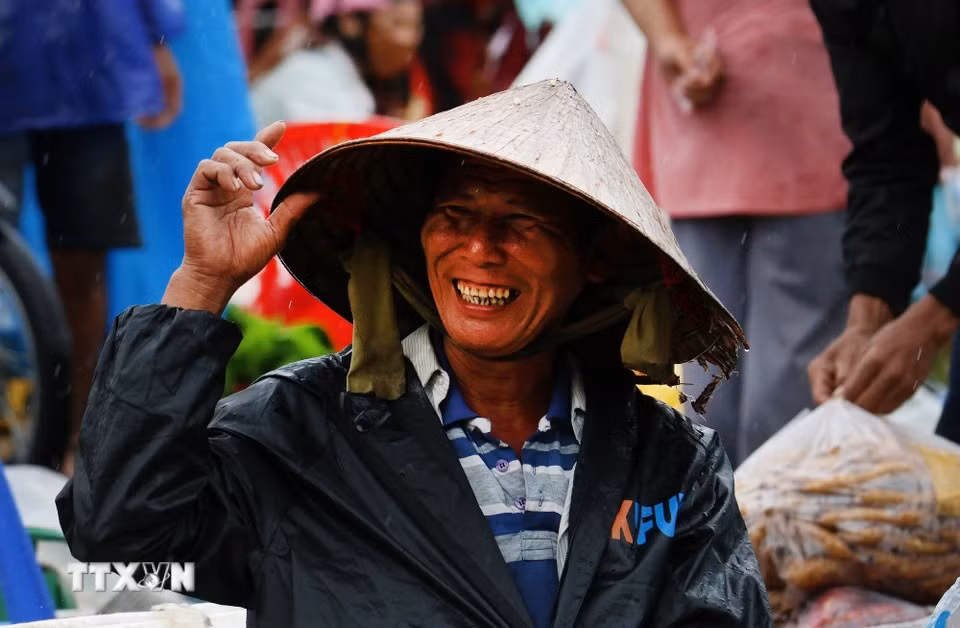 Vendors remain cheerful as they wait for customers beside their stalls, even on rainy days. (Photo: Duy Khuong/VNA)