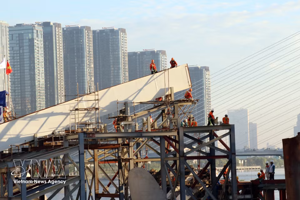 Engineers and workers at the construction site prepare for the joining of the bridge’s main span. (Photo: VNA)