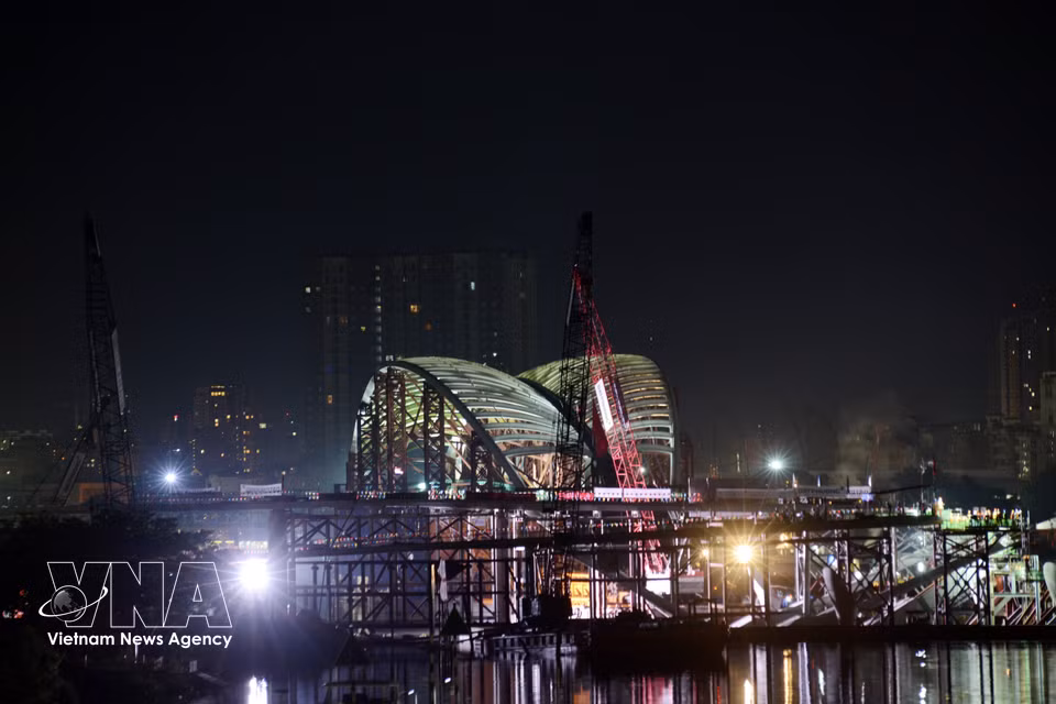 Workers release the moorings as specialised tugboats tow the barge carrying the main span towards the middle of the river. (Photo: VNA)