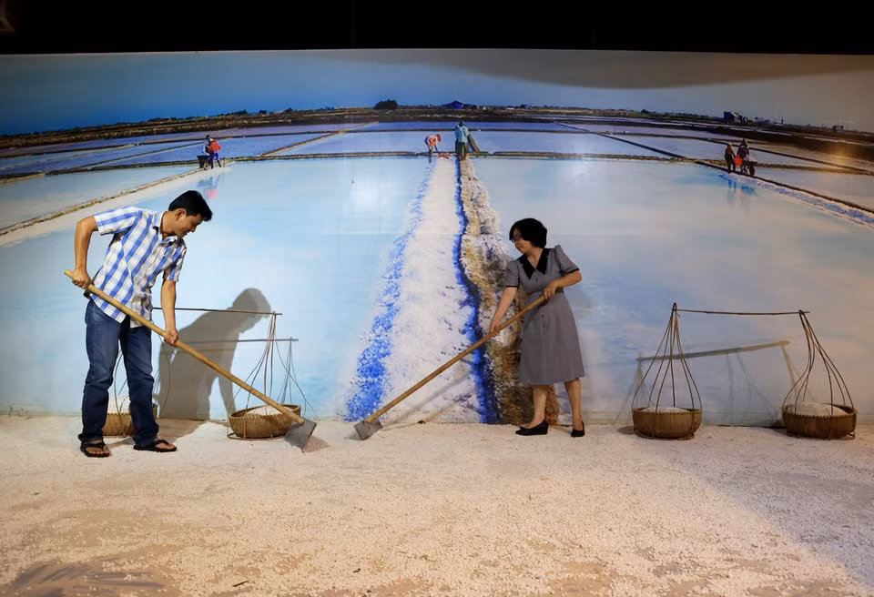 Tourists play the role of salt farmers in salt fields at the museum. (Photo: VNA)