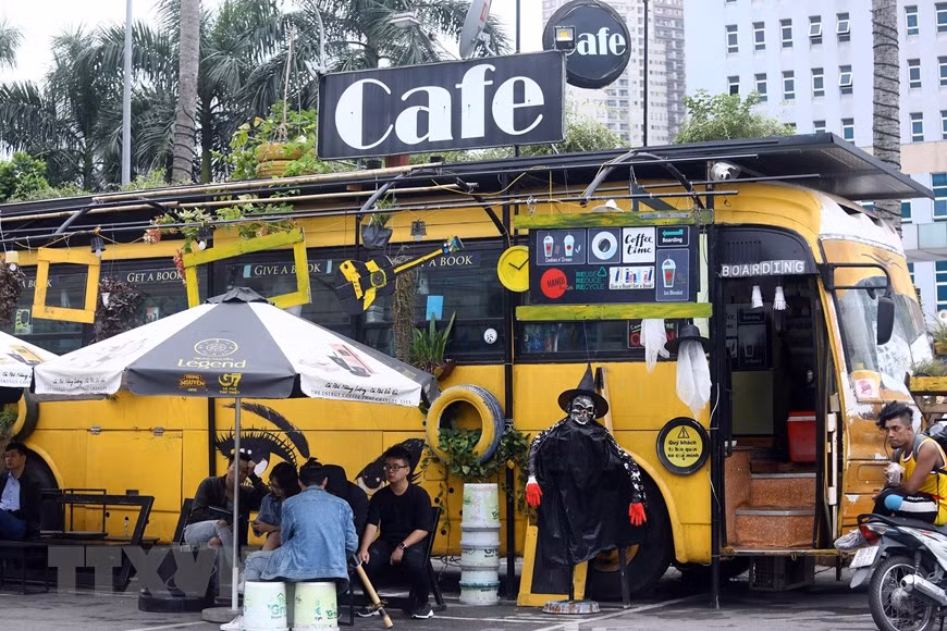 The coffee shop is constructed from an old refurbished bus, with paint barrels and old tires being made into tables and chairs (Photo:VNA) 