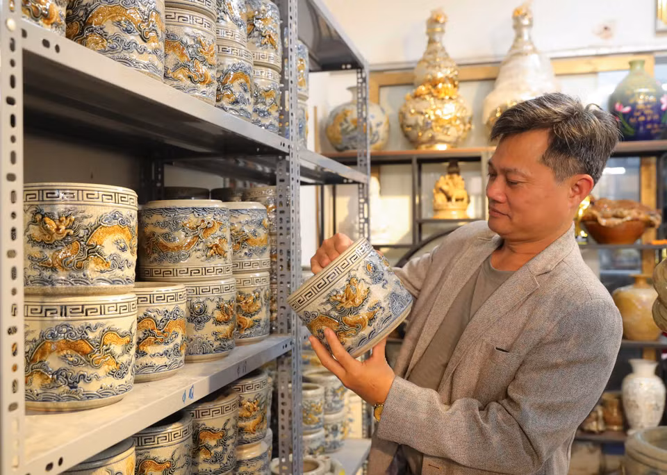 Customers choose dragon and phoenix-shaped incense burners adorned with glistening yellow enamel. (Photo: VNA)