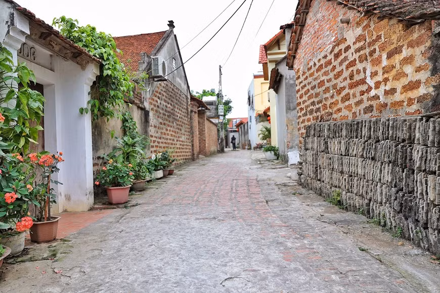 A brick path dyed in the colour of time in Duong Lam village. Laterites can be found almost anywhere in Duong Lam, becoming an integral part of the village. Laterite, the key material of walls, gates and wells, are abundant in Mong Phu hamlet, lying under fields, garden ponds, or deep down underground. The material, both a soil and a rock type rich in iron and aluminum, is often soft underground but getting harder over time once it is dug up to build houses. Houses’ walls and fences made of rough dark honey-brown brick-shaped laterites along the village road create a unique charm. (Photo: VietnamPlus)