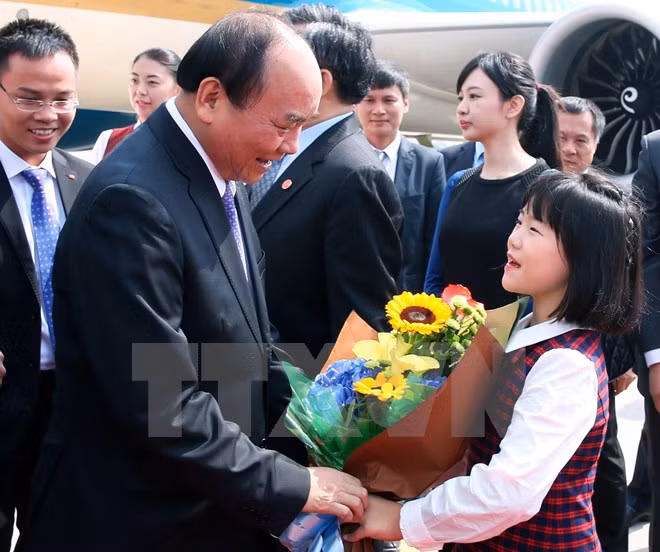 A Chinese girl presents flowers to PM Nguyen Xuan Phuc at Beijing Capital International Airport (Photo: VNA)