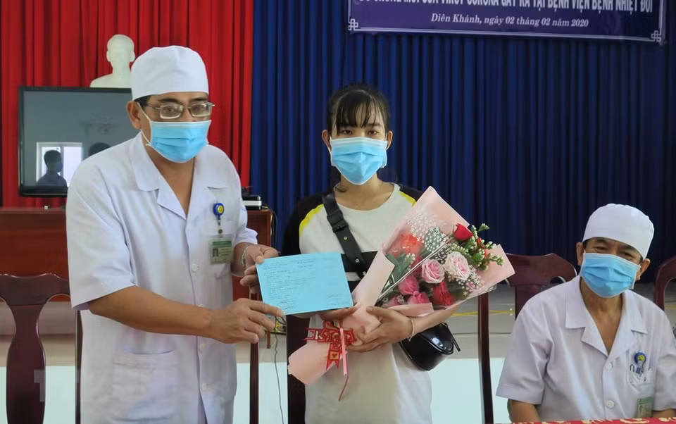 Deputy Director of Khanh Hoa Hospital of Tropical Diseases Nguyen Vu Quoc Binh presents flowers and hospital discharge certificate for patient Le Thi Thu H who recovered from disease caused nCoV after treatment (Photo: VNA)