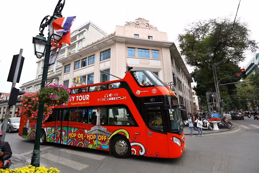 Many tourists go for double decker to enjoy the bustling atmospheres on Hanoi’s streets as the summit is nearing (Photo: VNA)