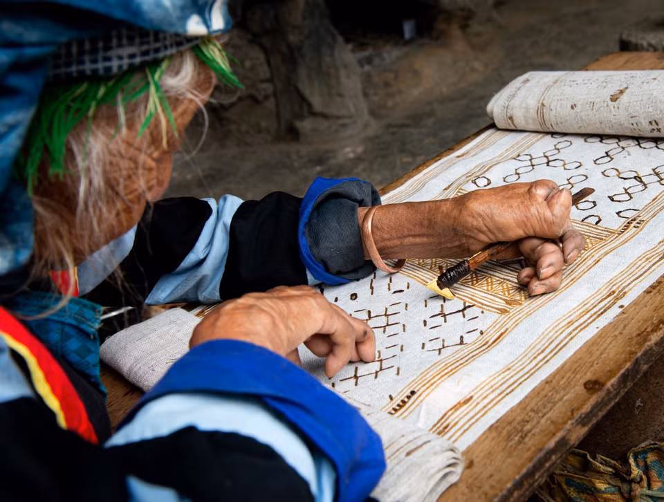 What makes the Mong-made flax clothing distinguishable from others is the sophisticated brocade patterns and the beeswax drawing. The craftswomen use heated beeswax to paint traditional decorative patterns of the Mong people on the sheets. (Photo: VNA)