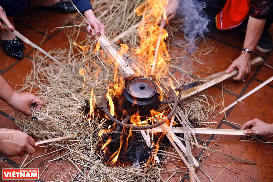 The rice pot is kept surrounded by burning straw (Photo: VNA)