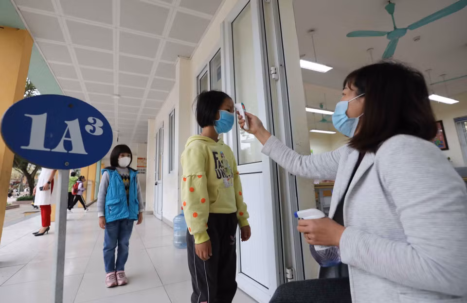 Body temperature of pupils at Ngoc Lam Primary School in Long Bien district are measured while their hands are sanitised before attending classes (Photo: VNA)