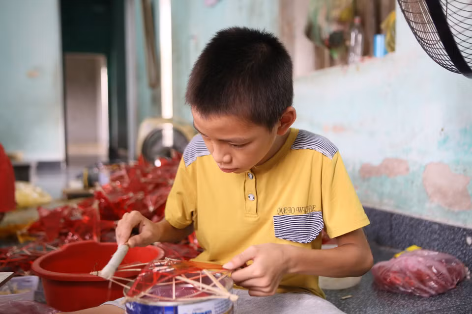 Children in Bao Dap village help their parents make star lanterns when not at school. (Photo: VNA)