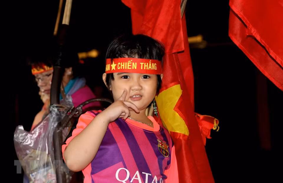 Parents bring the little ones along to celebrate the national team’s victory in Long An province (Photo: VNA)