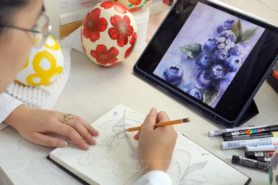 Hoang Chau sketches a design on paper before drawing on the fragile eggshells. (Photo: VNP/VNA)