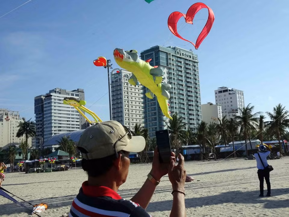 Tourists take photos of the flying kites (Photo: VNA)