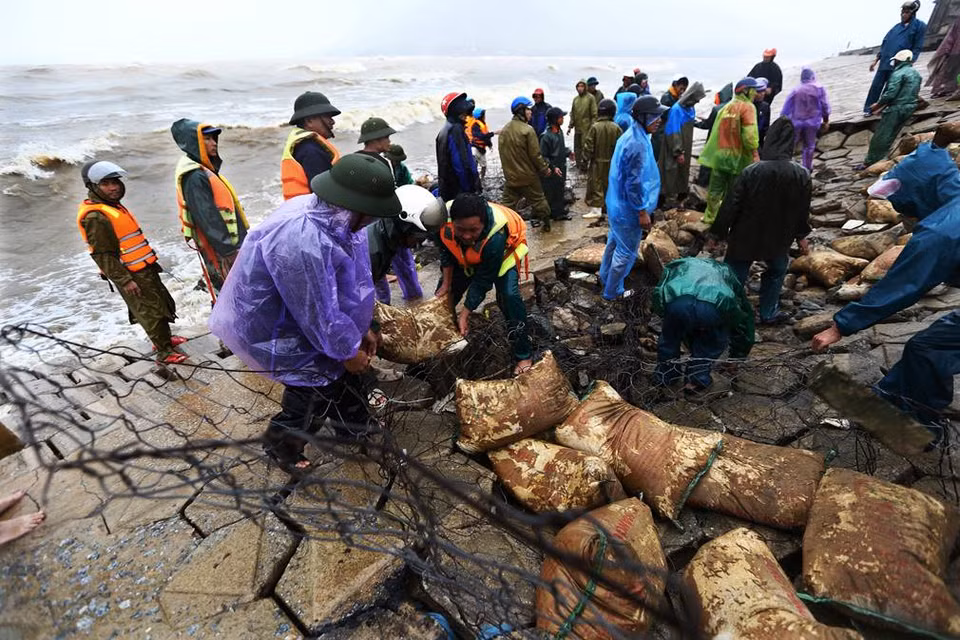 Armed forces coordinate with authorities and people in Cam Nhuong commune, Cam Xuyen district, Ha Tinh province to repair erosion areas of sea embankment, where many households live (Photo: VNA)
