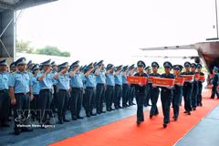 Officers and soldiers of the Air Defense - Air Force Service perform a salute as the remains of martyrs from localities within Military Region 9 are unloaded from the aircraft at Gia Lam military airfield in Hanoi on October 5, 2026. (Photo: VNA)