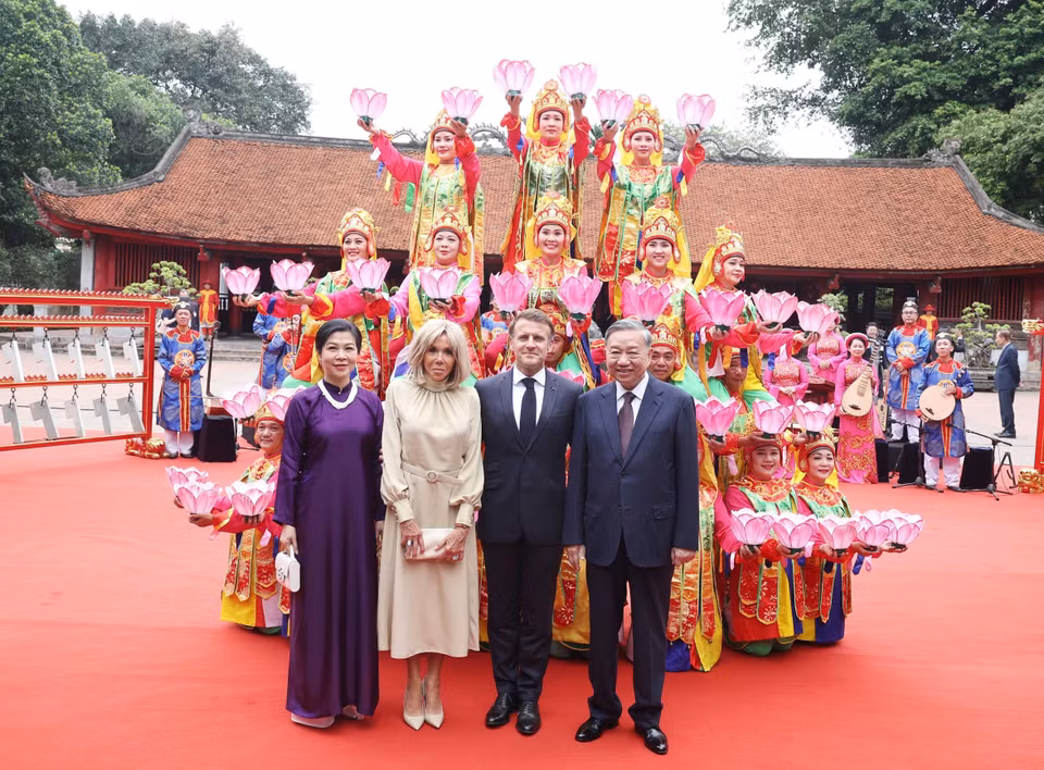 Party General Secretary To Lam and his spouse, together with French President Emmanuel Macron and his spouse, pose with artists performing royal court music at the Temple of Literature. (Photo: VNA)