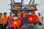 Vietnam Coast Guard officers present the national flag to fishermen at sea. (Photo: VNA)