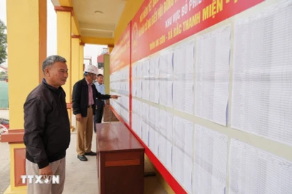 Voters review the lists of candidates and their brief biographies. (Photo: VNA) 