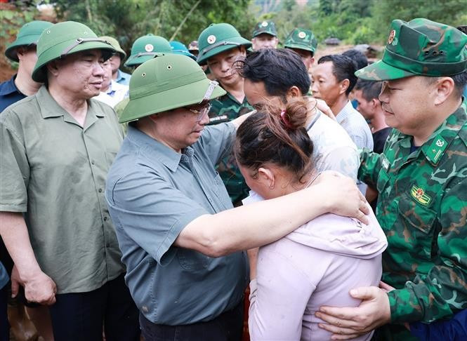 Prime Minister Pham Minh Chinh consoles a family whose member dies in recent floods in Xa Dung commune. (Photo: VNA)