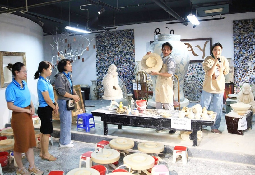 Visitors watch a traditional pottery-making demonstration at Bat Trang craft village. (Photo: hanoimoi.vn)