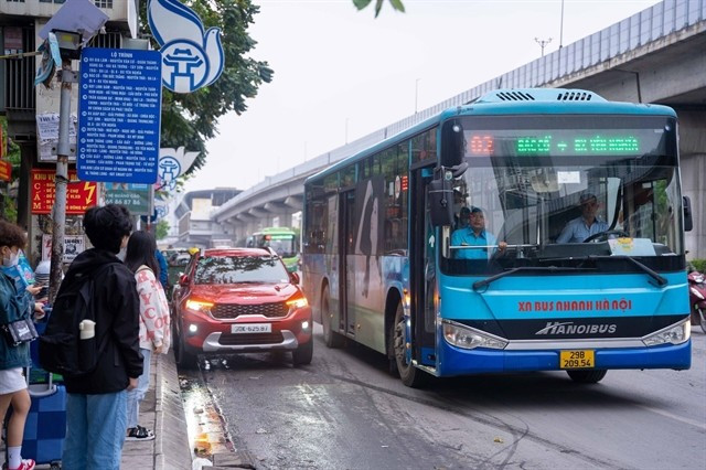 Passengers wait to board a bus in Hanoi (Photo: VNA). 