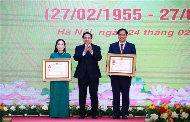 Prime Minister Pham Minh Chinh (C) presents the third-class Labour Order to Associate Professor Dr. Dao Xuan Co, Director of Bạch Mai Hospital, and the Meritorious Doctor title to Nguyen Thi Mai Ngoc, a doctor at the Vietnam National Heart Institute under Bach Mai Hospital. (Photo: VNA)