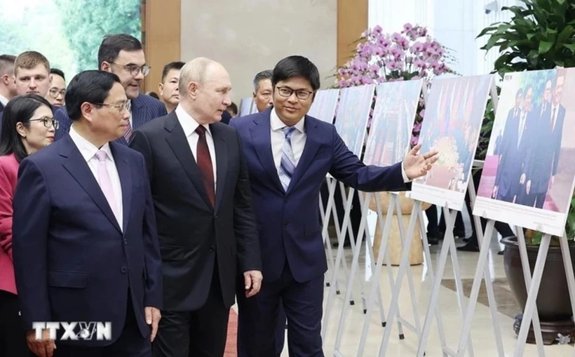 Prime Minister Pham Minh Chinh (L) and Russian President Vladimir Putin (C) visit a photo exhibition showcasing cooperation between the two countries. (Photo: VNA)