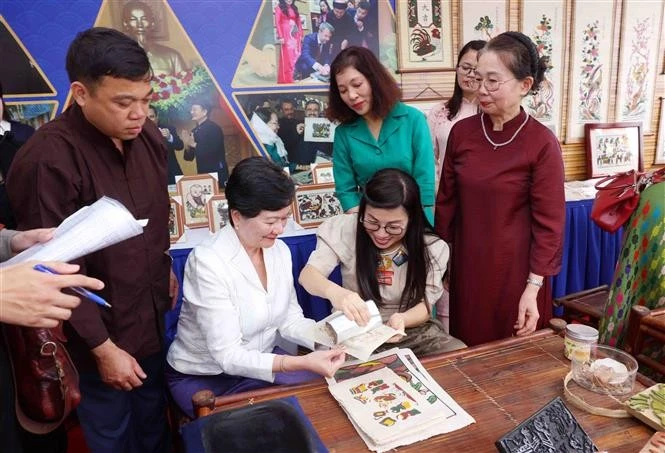 The spouse of Prime Minister Pham Minh Chinh, Le Thi Bich Tran, and delegates make Dong Ho folk paintings during their visit to Bac Ninh on April 21. (Photo: VNA)