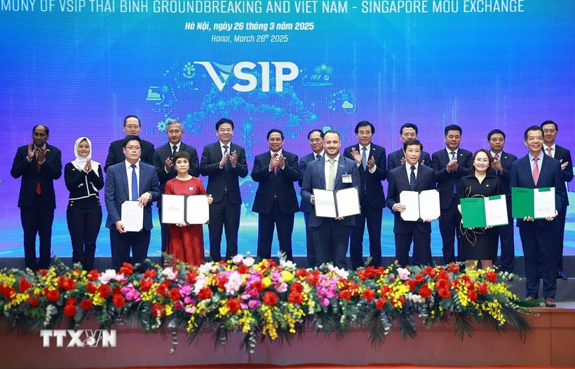 Prime Minister Pham Minh Chinh and his Singaporean counterpart Lawrence Wong witness the exchange of cooperative documents between Vietnamese and Singaporean enterprises in Hanoi on March 26. (Photo: VNA)