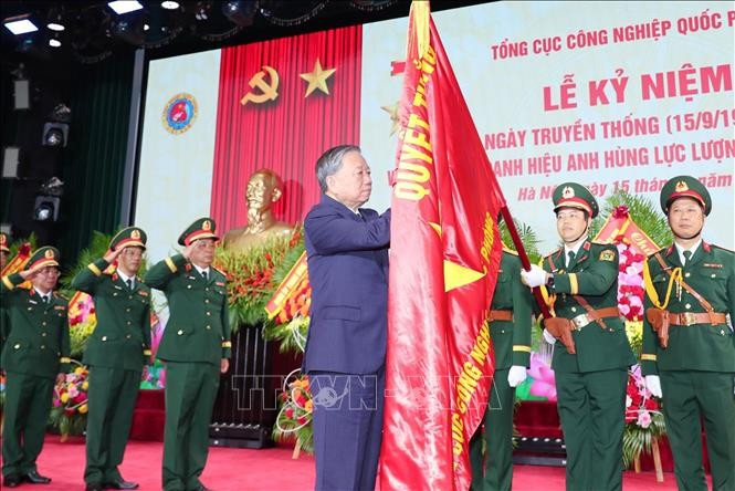 Party General Secretary To Lam sticks the Hero of the People's Armed Forces badge to the traditional flag of the General Department of Defence Industry. (Photo: VNA)