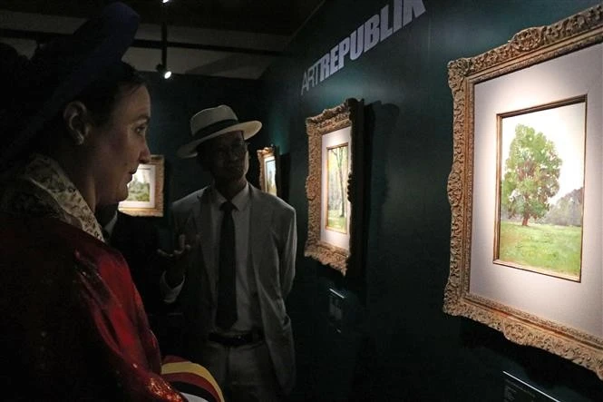 Amandine Dabat (left) - the fifth-generation descendant of King Ham Nghi and visitors contemplate paintings by King Ham Nghi. (Photo: VNA)