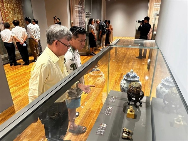 Visitors are captivated by the displays of rare antiques at the exhibition. (Photo: VNA)